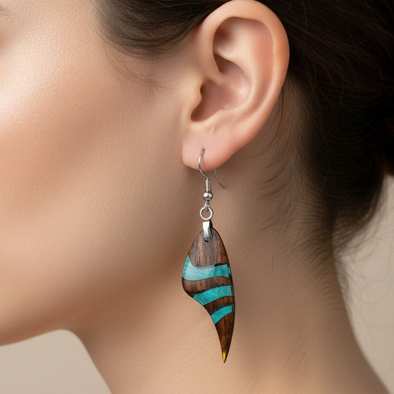 modelo lleva puestos pendientes largos de gancho elaborados en madera de palorosa y resina color azul turquesa transparente transparente y pulido en alto brillo con fornitura de metal acero inoxidable 316