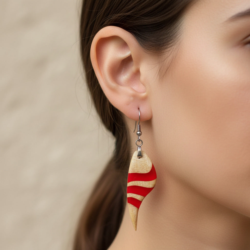modelo que lleva puestos pendientes largo de gancho elaborado en madera de arce americano y resina rojo intenso, con una fornitura de metal acero inoxidable 316