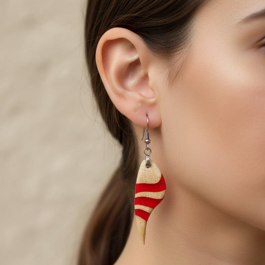 modelo que lleva puestos pendientes largo de gancho elaborado en madera de arce americano y resina rojo intenso, con una fornitura de metal acero inoxidable 316