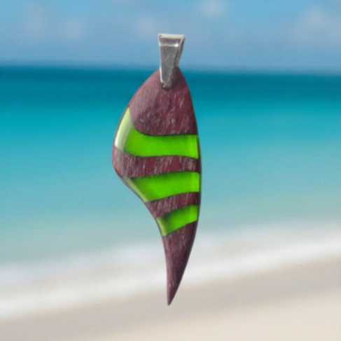 pendiente de madera amaranto y resina verde esmeralda con enganche de acero inoxidable en fondo de mar azul del caribe