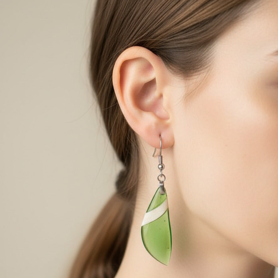 modelo lleva puestos pendientes largos de gancho elaborados en madera de arce y resina verde pistacho claro transparente y pulido en alto brillo con fornitura de metal acero inoxidable 316