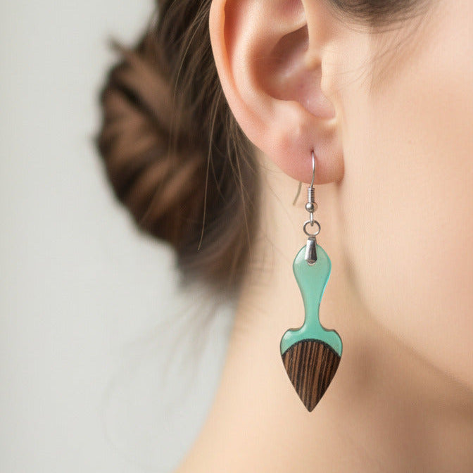 modelo lleva puesto pendiente elaborado en madera wengue con resina de azul claro translúcido, con fornitura de metal de acero inoxidable 316 